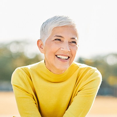 Senior woman with yellow shirt outside and smiling