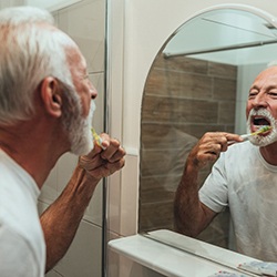 mature man brushing teeth for cost of dental implants in Rockwall  