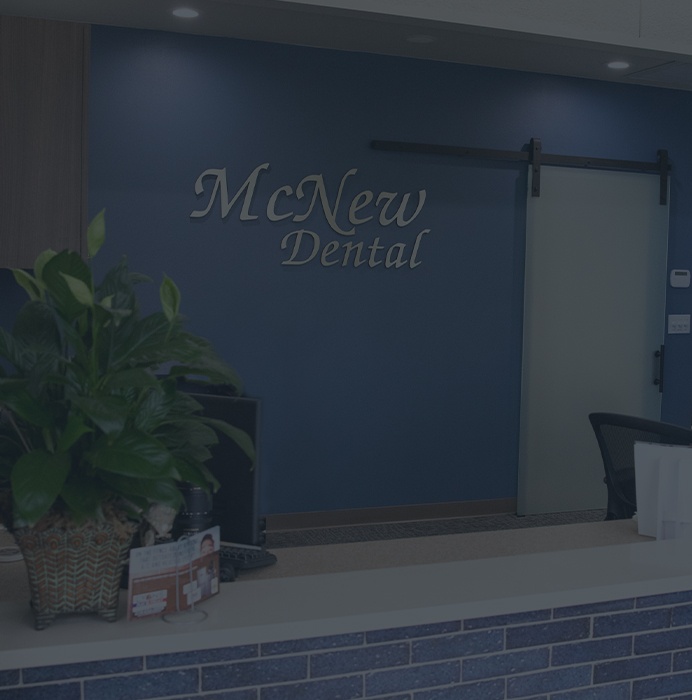 McNew Dental sign on wall behind dental office reception desk