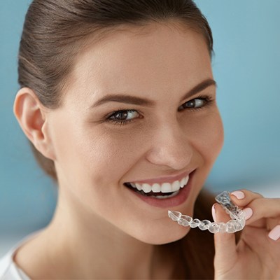 Woman holding an Invisalign clear braces tray