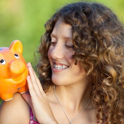 Woman with braces looking at a piggy bank
