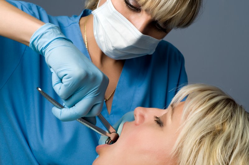 A dentist performing a tooth extraction in Rockwall