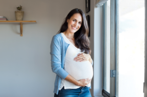 a pregnant woman smiling and holding her belly